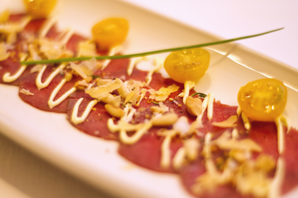 Carpaccio de venado con mantequilla de naranja, almendras y piñones tostados con tomillo y lascas de gouda viejo.