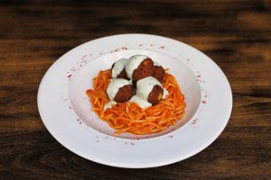 Albóndigas de tofu y espinacas sobre espaguetis de arroz, salsa picante y yogur