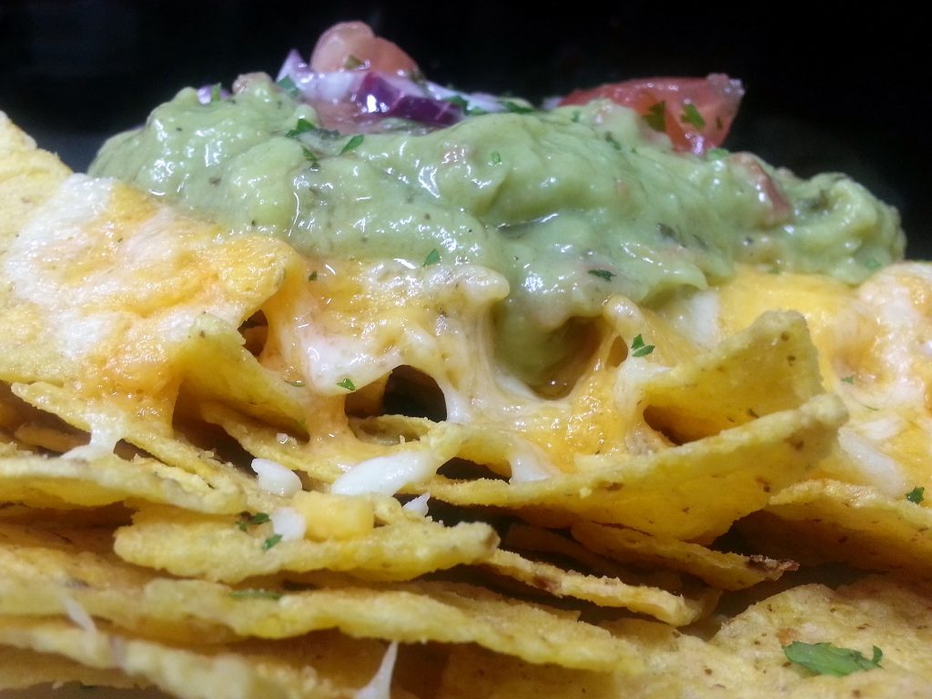 Nachos de maíz con mezcla de quesos fundidos y cubiertos de alubias con carne